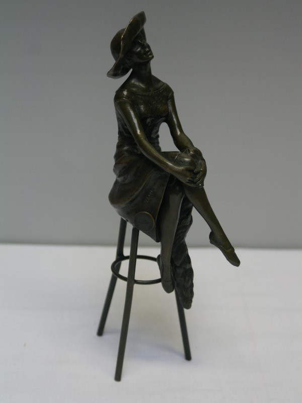 Bronzen sculptuur van vrouw op barkruk met hoed (Art. nr. 629)