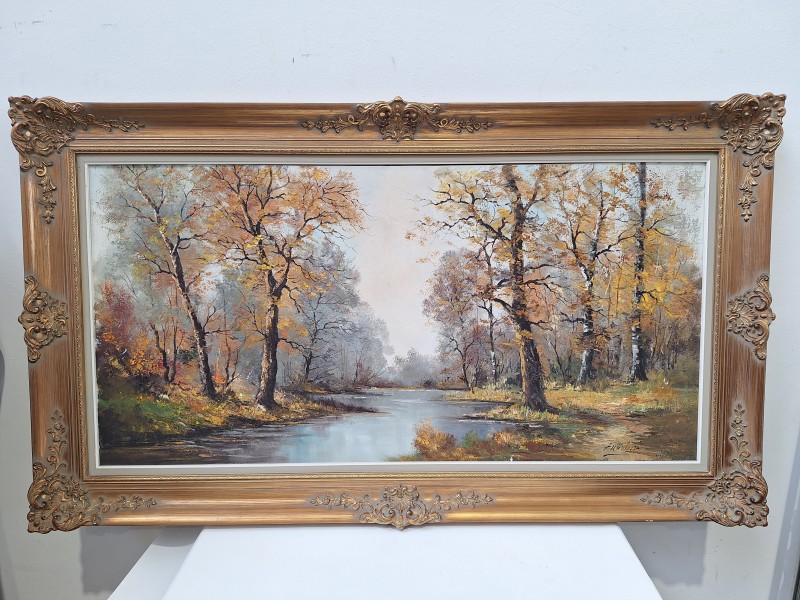 Groot olieverfschilderij van bomen langs een rivier in een vergulde kader