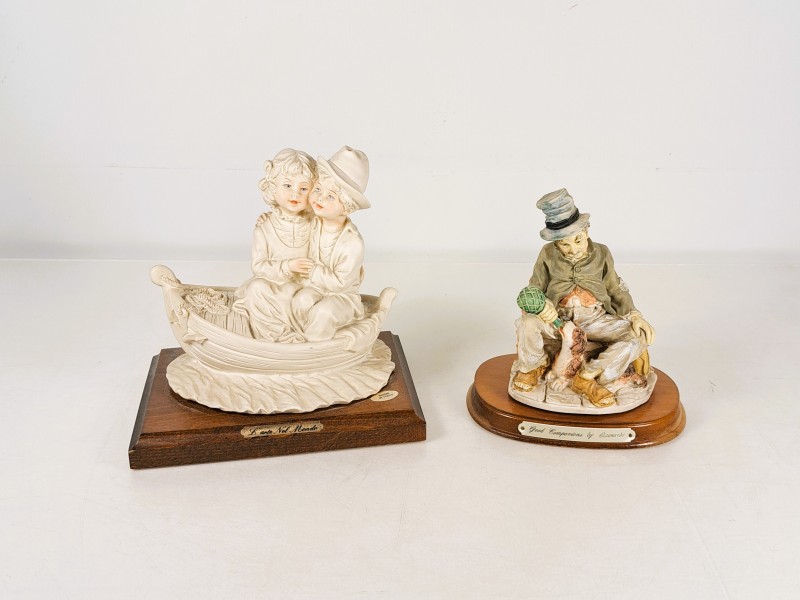 Twee decoratieve beeldjes op houten sokkel – L’arte Nel Mondo en Leonardo(I)